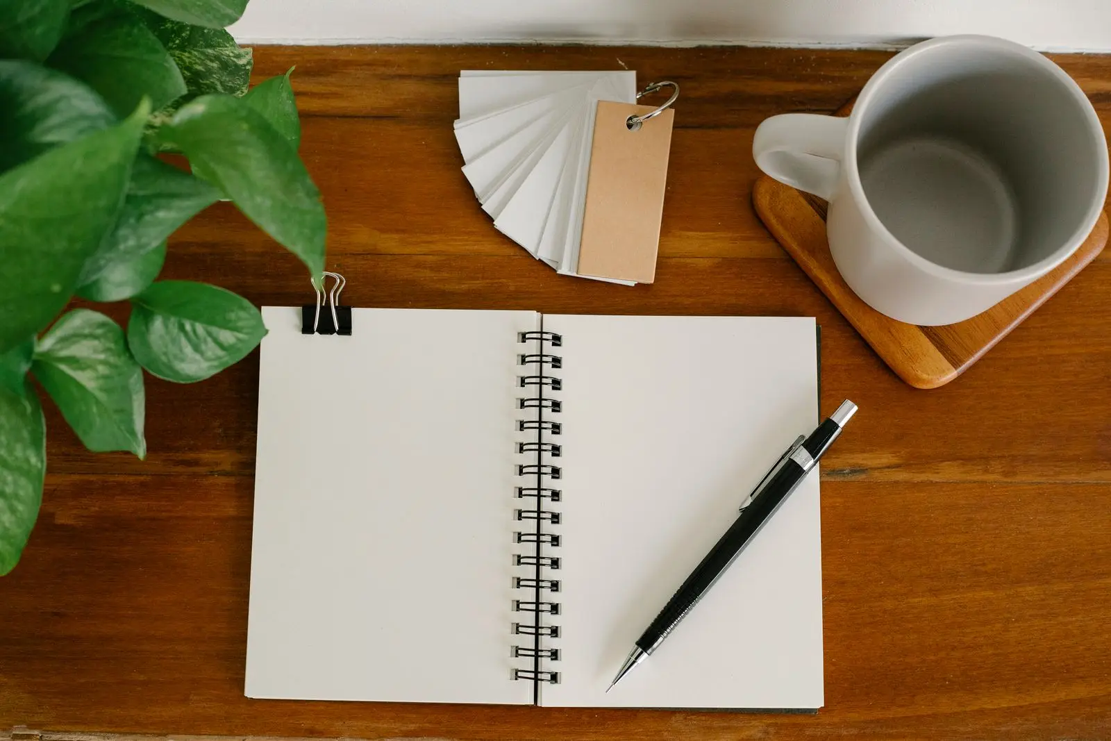 Cuaderno, lapicero y taza sobre escritorio